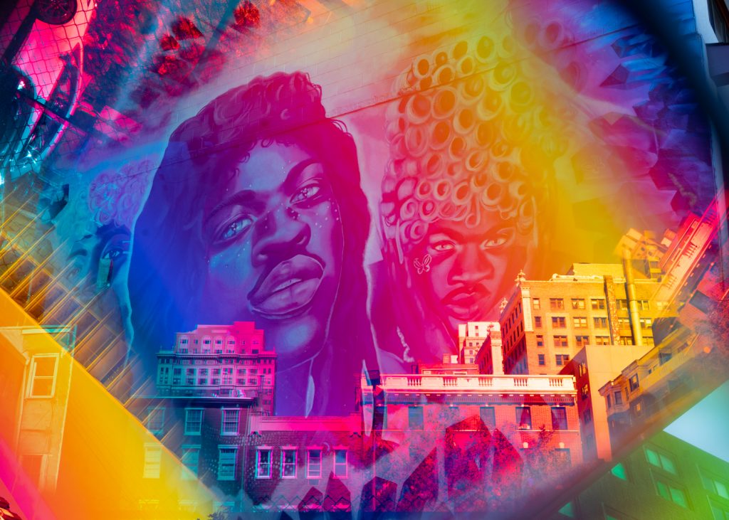 Chromatic prism photo setting Lil Nas X Mural by #asheyeart on Writer's Block Rehab bar wall over city skyline 